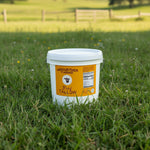 White bucket labeled Meriwether Farms Beef Tallow on a grassy field
