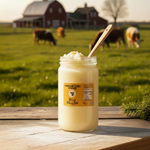 Meriwether Farms Beef Tallow Jar outside on a table overlooking a field of cows grazing. 